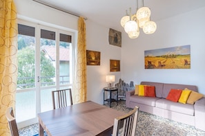 A room with a dining table, sofa, and artwork on the walls.