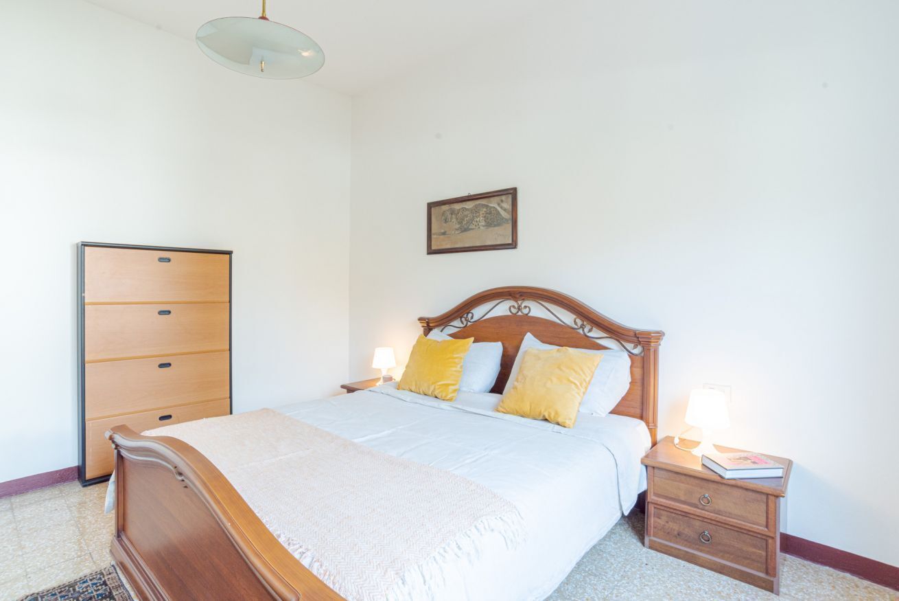 Une chambre à coucher avec un lit en bois, des tables de chevet, une armoire et un luminaire fixé au plafond.