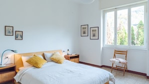 Ein Schlafzimmer mit einem Bett, Nachttischen, einem Sessel und gerahmten Bildern an der Wand.