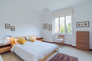 Une chambre à coucher comprenant un lit, des tables de chevet, une chaise, une armoire et une fenêtre donnant sur un beau paysage.