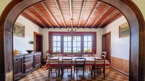 Ein Esszimmer mit Schachbrettmuster-Boden, Holzbalkendecke und einem Tisch für sechs Personen.