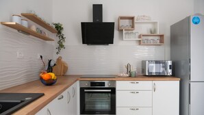 Una cocina moderna con armarios blancos, horno empotrado, microondas y refrigerador de acero inoxidable.