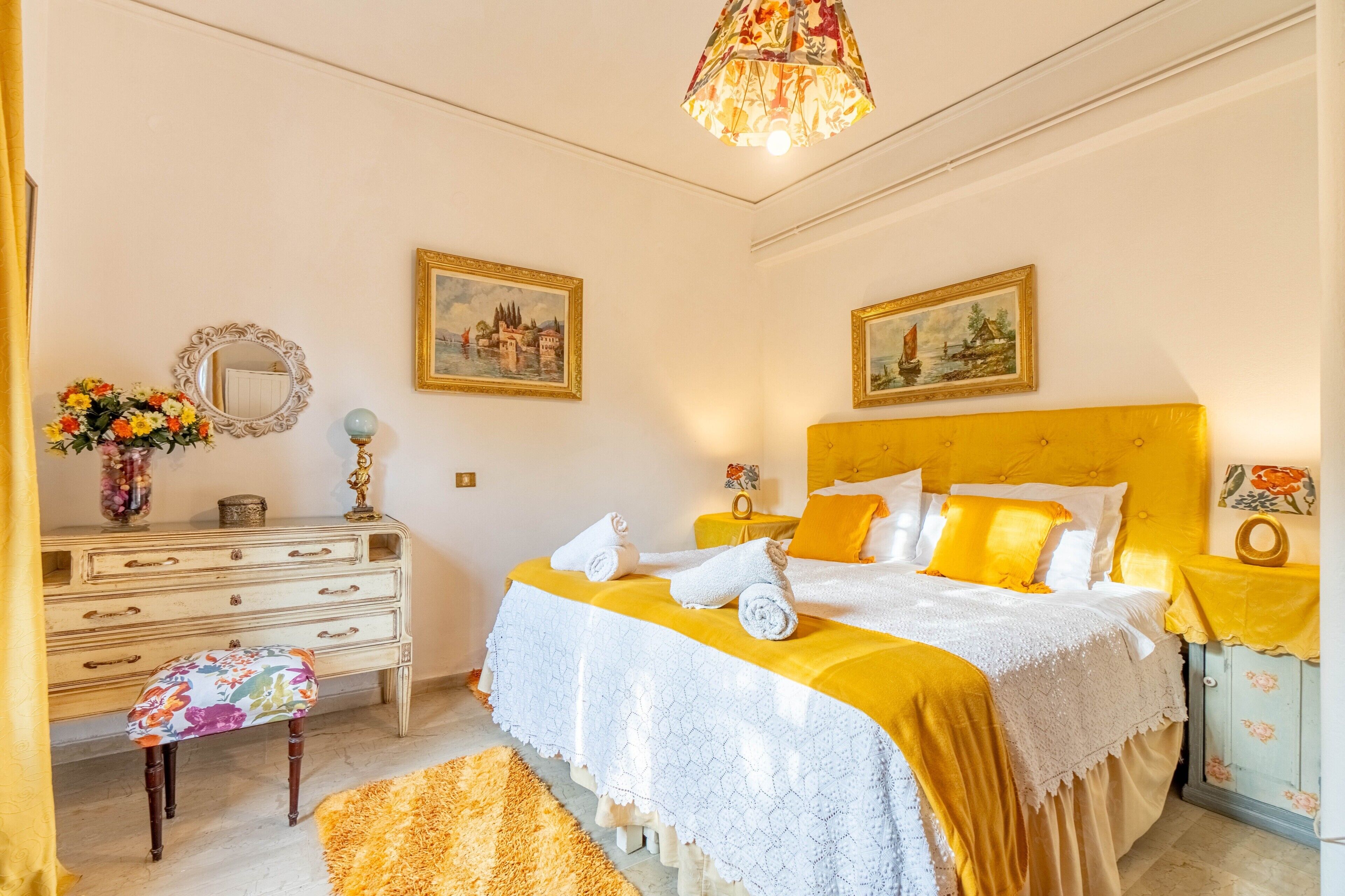 Un dormitorio con una cama, un aparador, un espejo y dos cuadros en la pared.