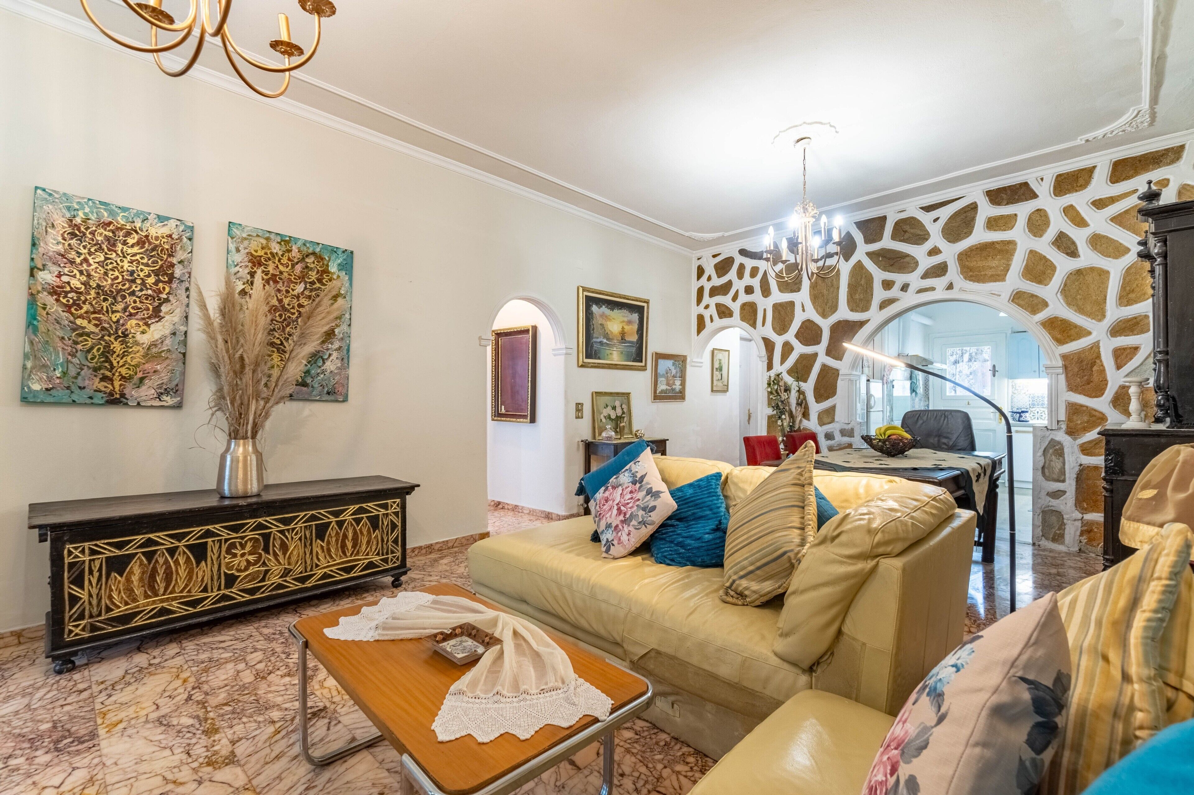 A living room with a sofa, coffee table, decorative vase, and artwork on the wall.