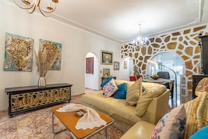 Een woonkamer met een bank, salontafel, decoratieve vaas en kunst aan de muur.