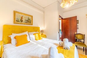 Une chambre dâhĂŽtel avec un grand lit, un tableau au mur, une porte en bois et une chaise.