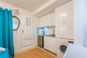 A compact kitchen with a washing machine, a sink, and cabinets.