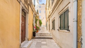 Une rue étroite pavée de pierres, avec des bâtiments de chaque côté et un escalier menant à un niveau supérieur.