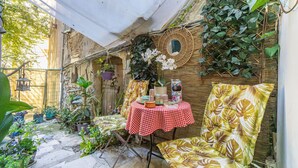 Un espace extérieur abrité, aménagé avec une table, des chaises et des plantes en pot.