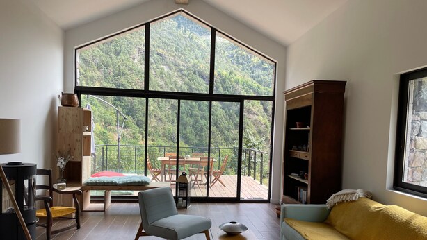 Un salon spacieux avec une grande fenêtre, un canapé, une table et une bibliothèque.