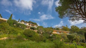 Propiedad en una ladera con un edificio que cuenta con varios balcones, rodeada de abundante vegetación y árboles.