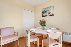 Un coin repas avec une table ronde, quatre chaises, une plante en pot et un tableau accroché au mur.