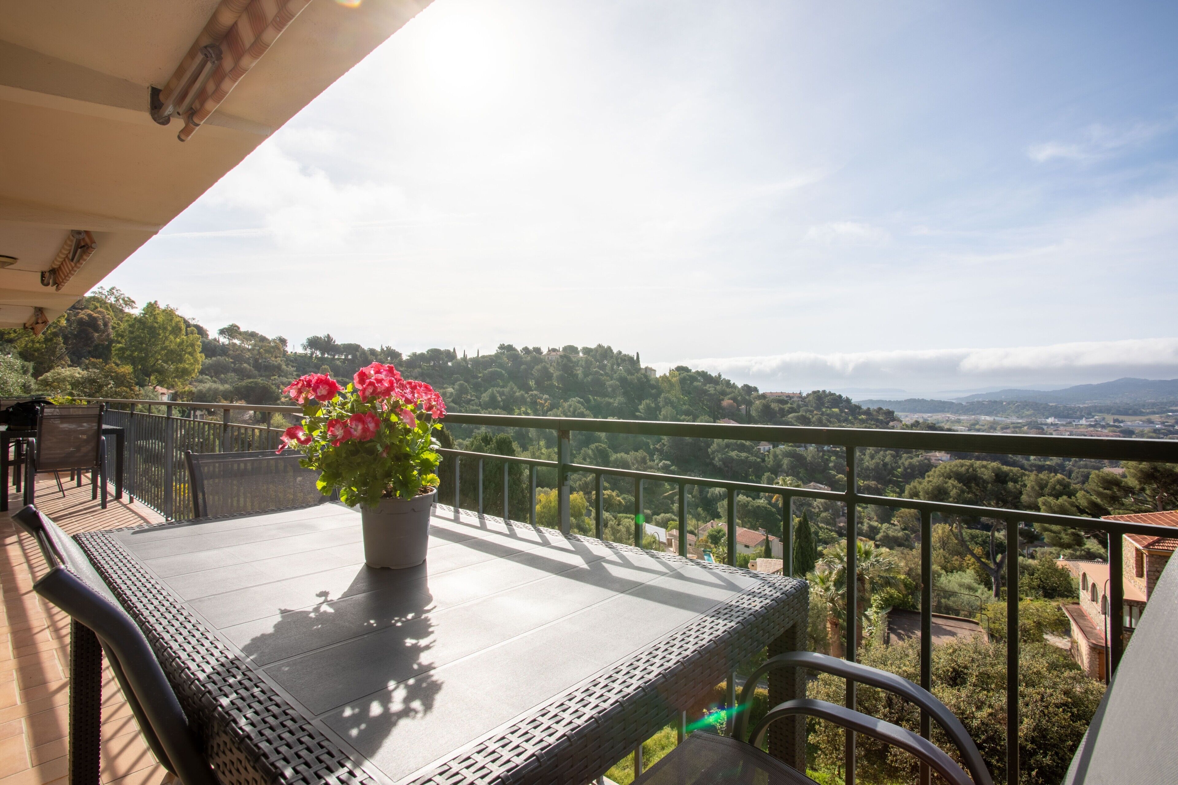 Un balcon avec un pot de fleurs, une table et des chaises.