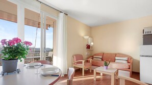 Un apartamento moderno con balcón, zona de comedor, sofá y cocina.