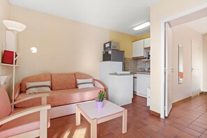 A compact living space with a sofa, a small table, a kitchen area, and a dining table.