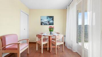Een eetgedeelte met een tafel gedekt voor vier personen, stoelen, een potplant en een schilderij aan de muur.