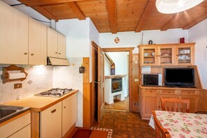 A kitchen with wooden cabinets, a stove, a microwave, and a dining area with a table and chairs.