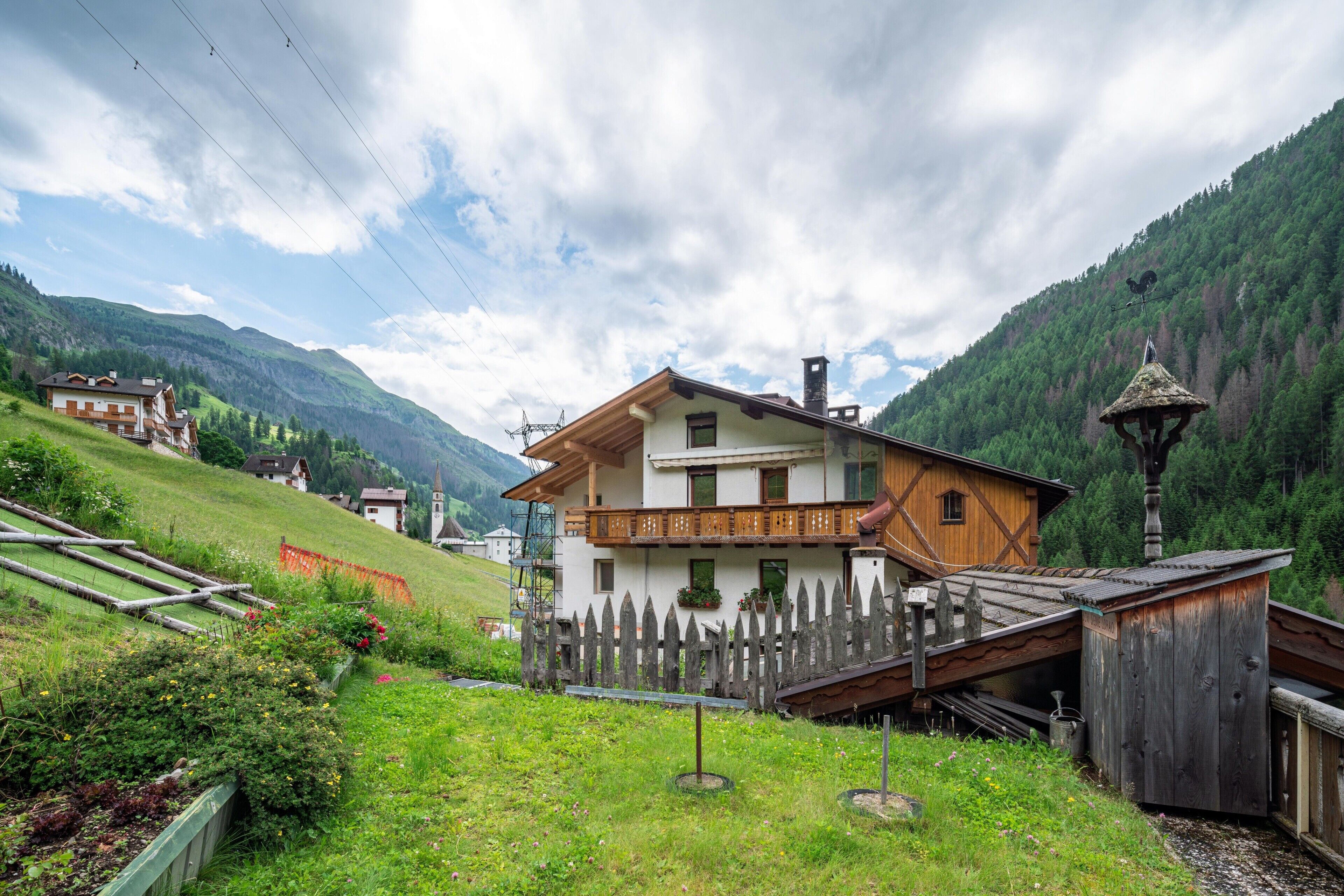 Un tipico chalet con balcone in legno, immerso nel verde e con vista sulle montagne.