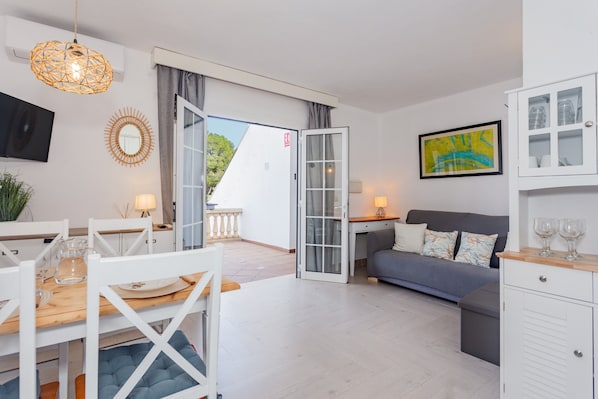 Un salon moderne comprenant un coin repas, un canapé et un meuble avec des portes en verre.