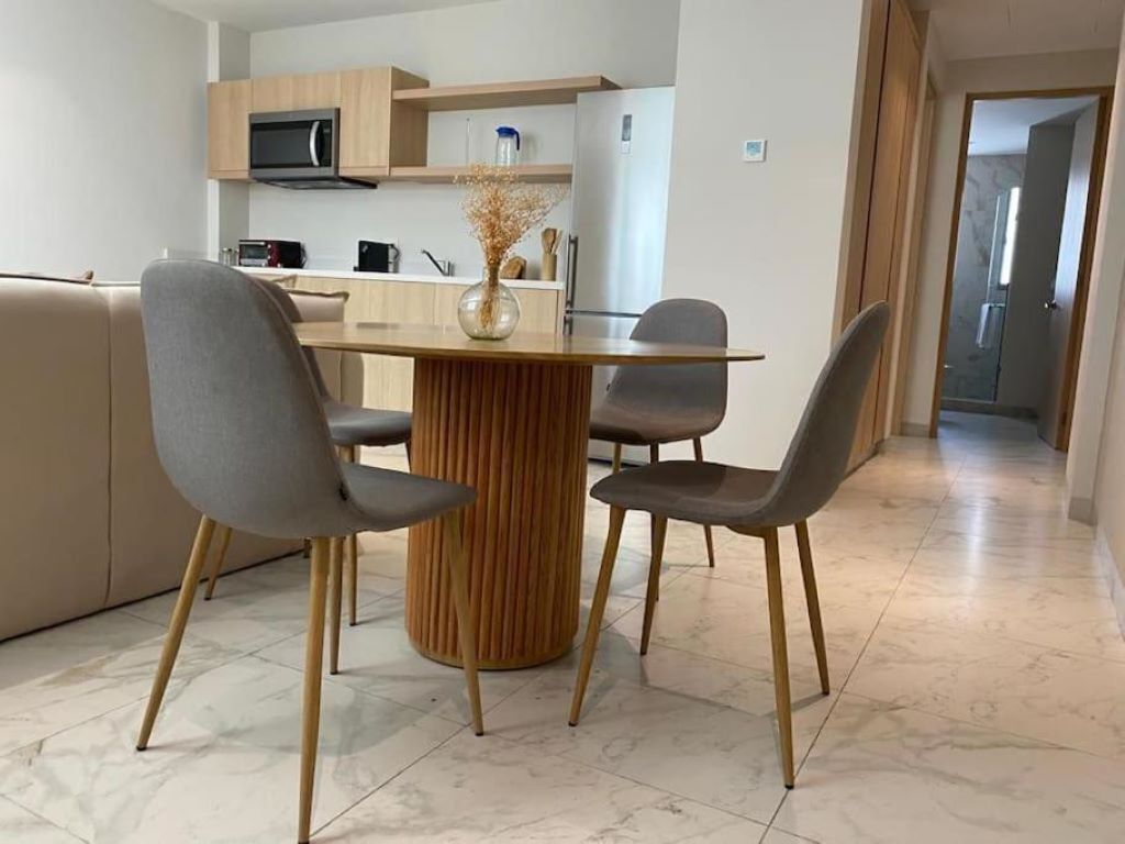 A modern kitchen with a dining table, four chairs, and a microwave.