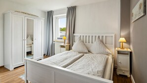 A bedroom with a bed, bedside tables, a wardrobe, and a window with curtains. - Lovely apartment in Malchow with WiFi (Malchow)