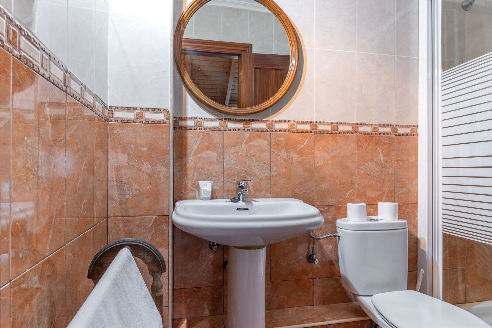 Une salle de bain équipée d’un lavabo, d’un miroir, de toilettes et d’un porte-serviettes.