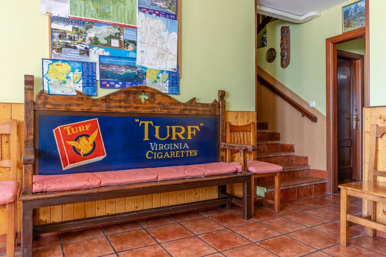 A wooden bench with a sign for 'TURF Virginia Cigarettes' and a map on the wall.
