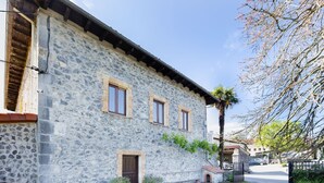 A stone building with a wooden door, windows, and a small porch area. - Rural House 'Trasmiera' with Private Terrace, Private Garden and Wi-Fi (Solórzano)