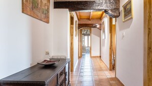 A hallway with a tiled floor, a wooden bench, and a door at the end. - Rural House 'Trasmiera' with Private Terrace, Private Garden and Wi-Fi (Solórzano)