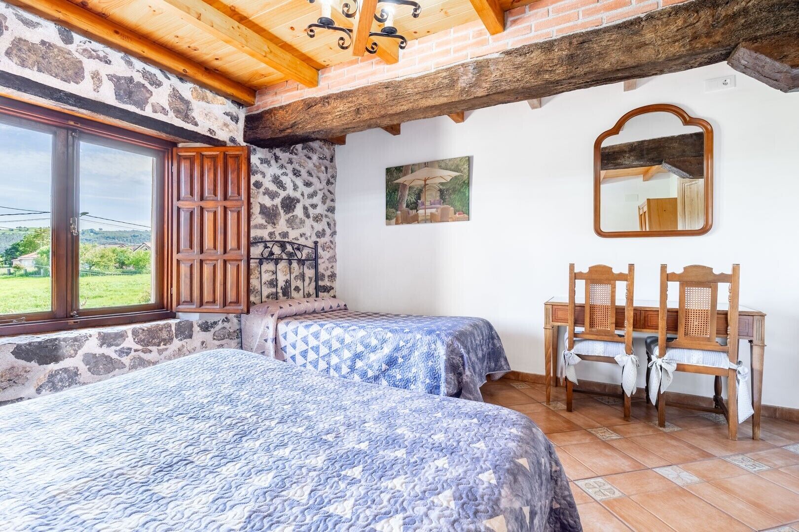 A bedroom with two beds, a stone wall, a wooden ceiling, a large window, and a mirror.