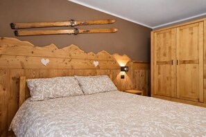 Una camera da letto con una testiera in legno, un letto con biancheria a motivi, un comodino e un armadio.