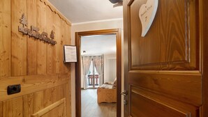 A wooden hallway with a wooden door, a heart-shaped sign, and a bed in the background. - Roccia Viva 4061 Maison Gerard Apartment with Mountain View, Garden, and Wi-Fi (Cogne)