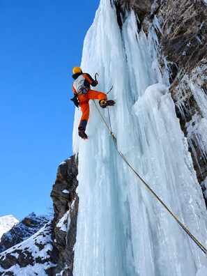 A climber in orange gear ascending a steep, icy rock face. - Holiday Home '4061 Maison Gerard Roccia Viva' (Cogne)