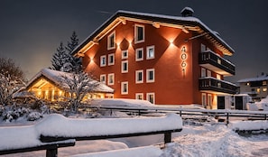 Un hotel a più piani con facciata rossa, numero 4061, con balconi e un paesaggio innevato.