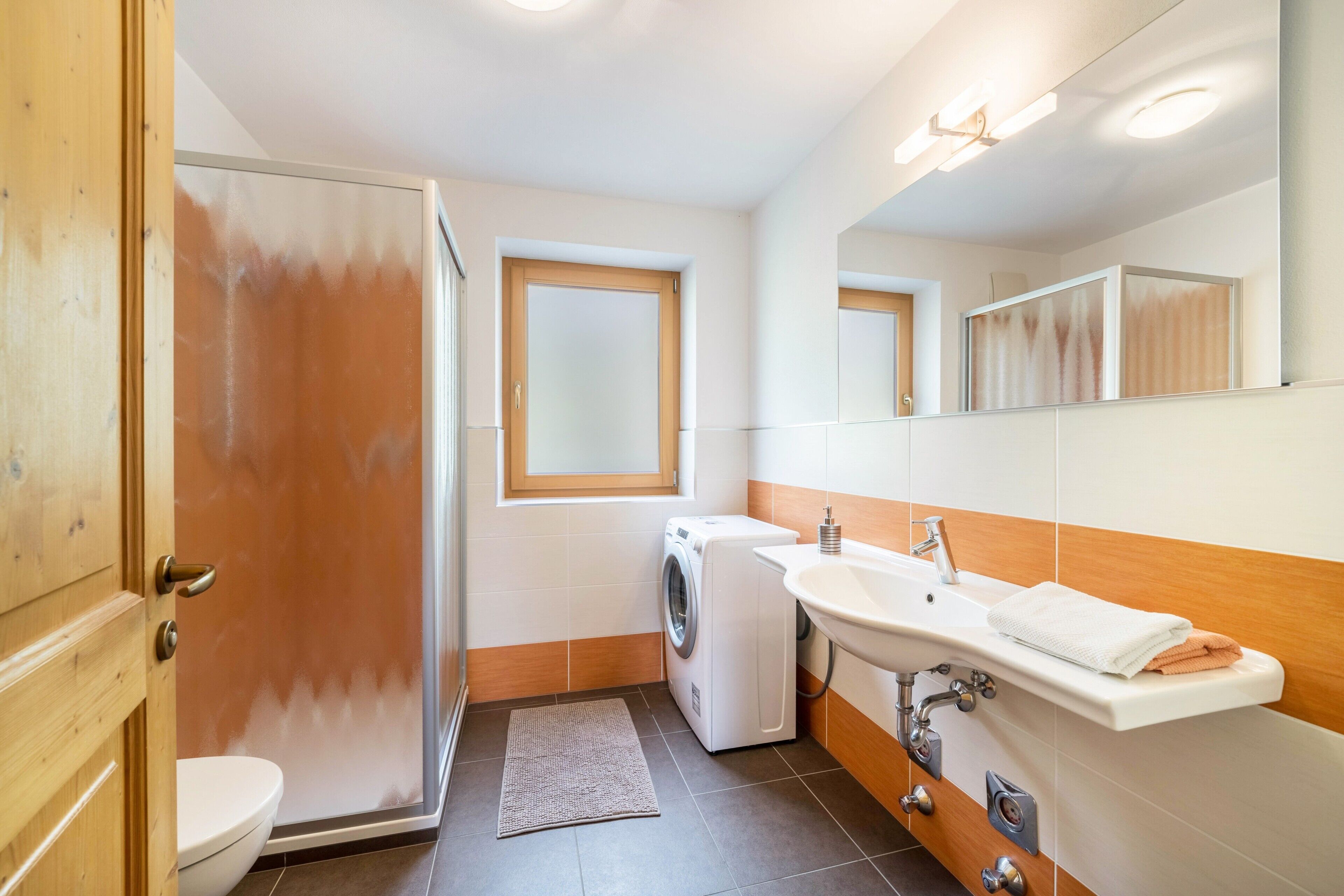 Un baño pequeño con lavadora, lavamanos e inodoro.