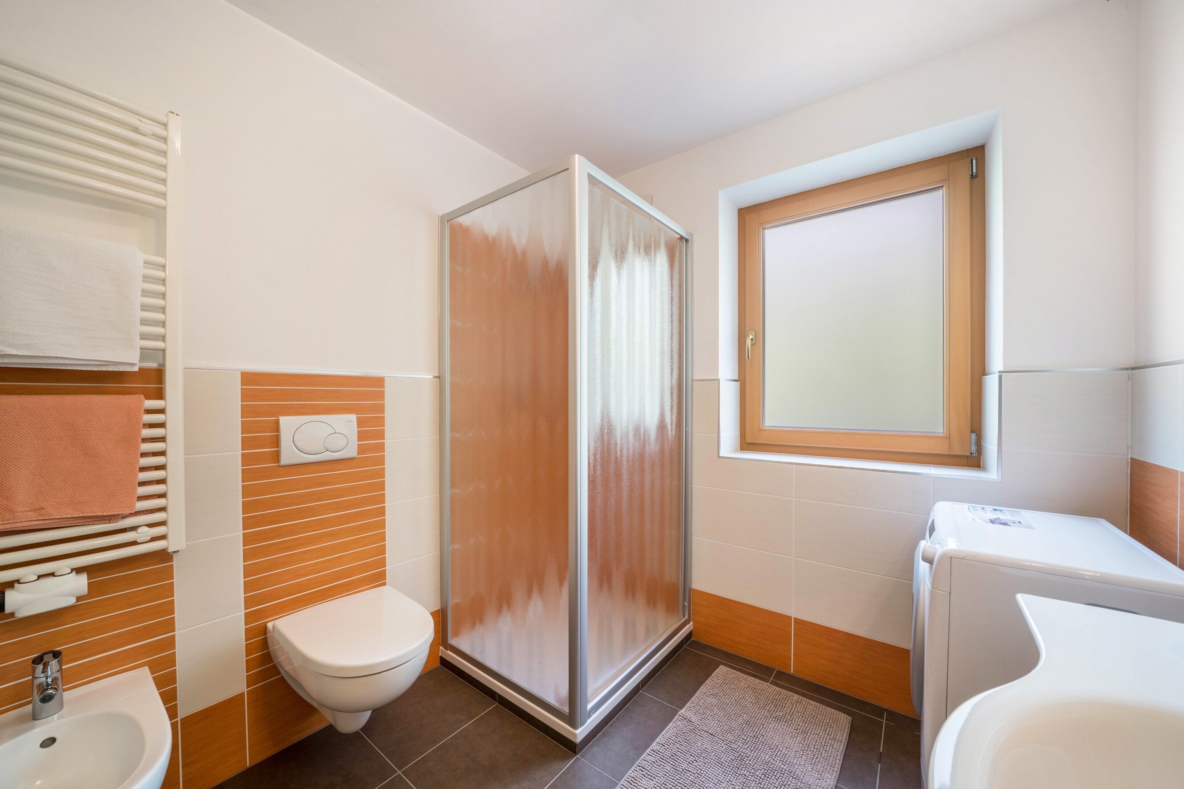 Ein Badezimmer mit Toilette, Waschbecken, Dusche und einem Fenster.