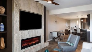 A modern living room with a fireplace, a flat-screen TV, and a dining area. - Carlsbad | Quiet Coastal Retreat | Pool + Ocean (Carlsbad)