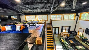 A spacious living area with a pool table, comfortable seating, a staircase, and large windows offering natural light. - Black Pearl Lodge @ DeGray. Small event venue or fun family getaway! (Bismarck)
