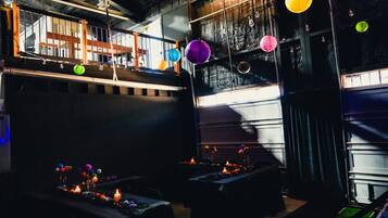 A dimly lit room with tables set up for dining, featuring a high ceiling and exposed beams.