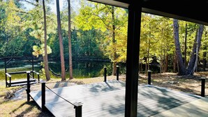 A covered wooden deck with a view of a lake and forest. - Black Pearl Lodge @ DeGray. Small event venue or fun family getaway! (Bismarck)