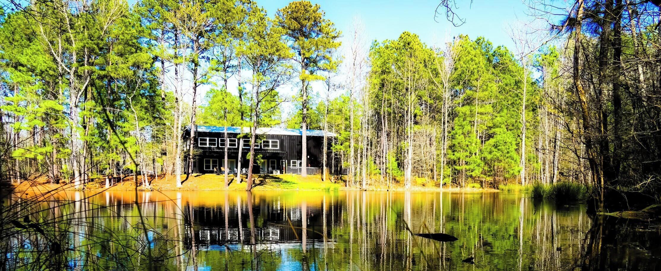 Uma cabana com um cais, rodeada por uma floresta e um lago.