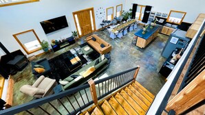 A spacious living area with a large sofa, a dining table, and a kitchen area with a refrigerator and sink. - Black Pearl Lodge @ DeGray. Small event venue or fun family getaway! (Bismarck)