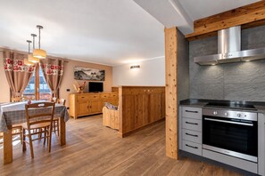 A modern kitchen with a built-in oven, wooden cabinets, and a dining area with a table and chairs.
