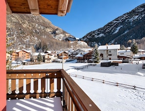 A snow-covered mountain village with wooden buildings and a clear blue sky.