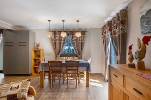 A dining area with a table, chairs, and a view through curtains.