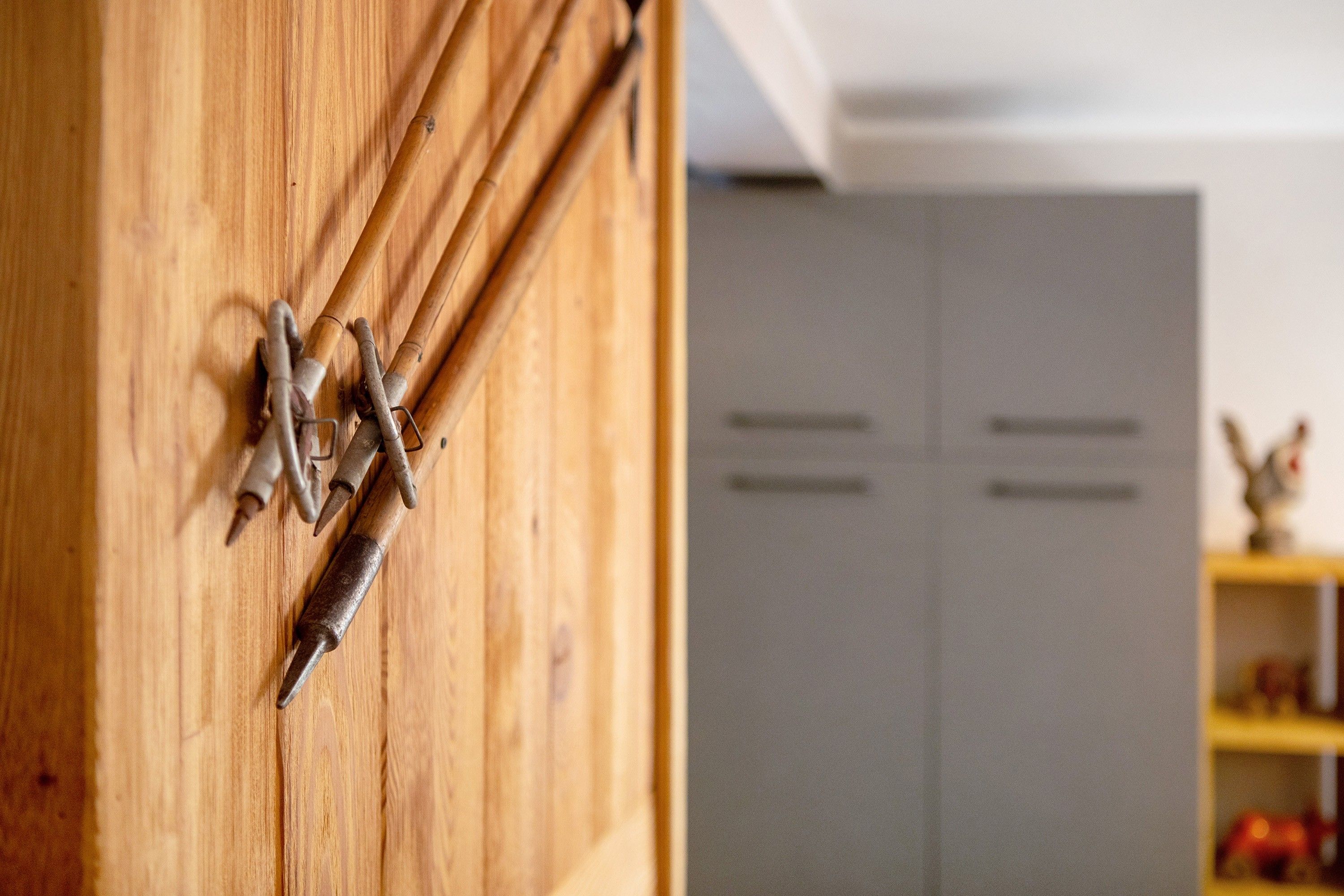 A wooden door with metal handles and a white cabinet in the background.