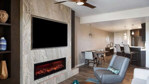 Ein modernes Wohnzimmer mit Kamin, Flachbildfernseher und Essbereich.