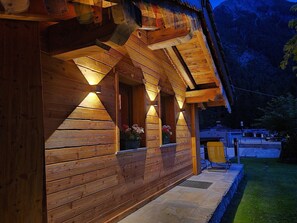 Une cabane en bois dotée d’une véranda, de meubles d’extérieur et offrant une vue sur les montagnes.