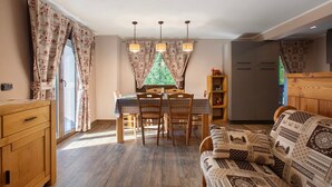 Een eetruimte met een tafel, stoelen en uitzicht door een raam.