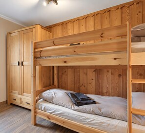 Una cama litera con un armario de madera al lado.